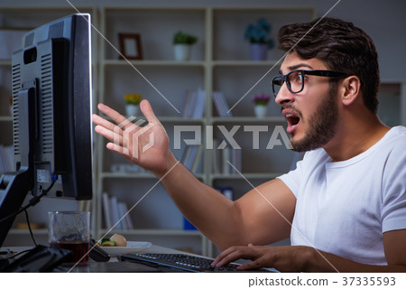 Young man staying late in office to do overtime 37335593