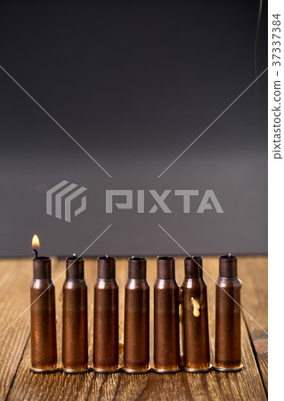 Burning candles and empty rifle cartridges. 37337384