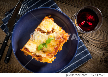 Piece of tasty hot lasagna with red wine. Piece of tasty hot lasagna with red wine. 37347528