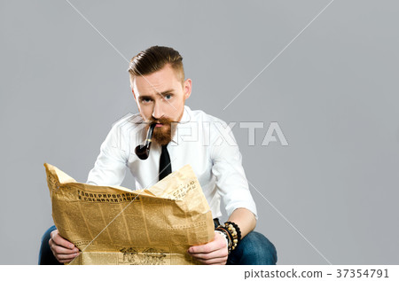 Stylish guy with a pipe reads old newspaper Stylish guy with a pipe reads old newspaper 37354791