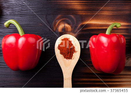Two sweet red pepper and a wooden spoon with chili 37365455