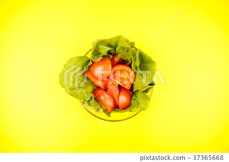 Glass bowl with salad leaves and sliced tomatoes 37365668