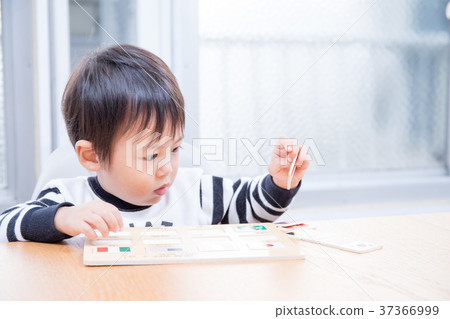 Toddler playing with national flag puzzle at dining table 37366999
