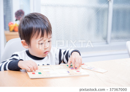 Toddler playing with national flag puzzle at dining table 37367000