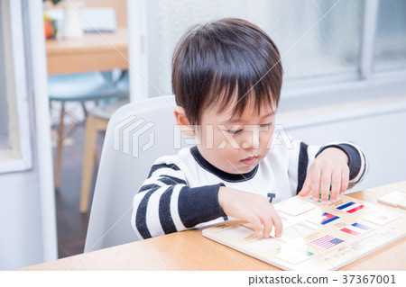 Toddler playing with national flag puzzle at dining table 37367001