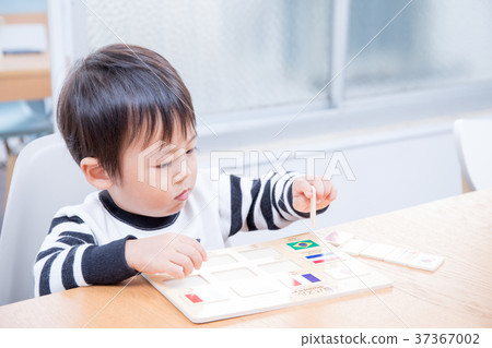 Toddler playing with national flag puzzle at dining table 37367002