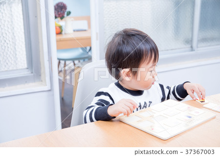 Toddler playing with national flag puzzle at dining table 37367003