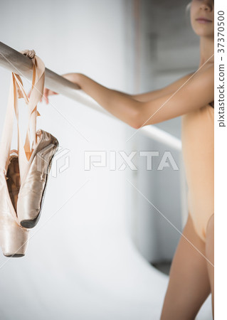 The girl is training near the ballet barre. 37370500