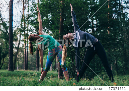 Female friends practicing yoga outdoors doing 37371531