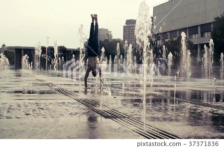 Strong man performing handstand in the fountain 37371836