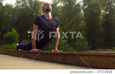 A man doing yoga exercises in the park 37372608