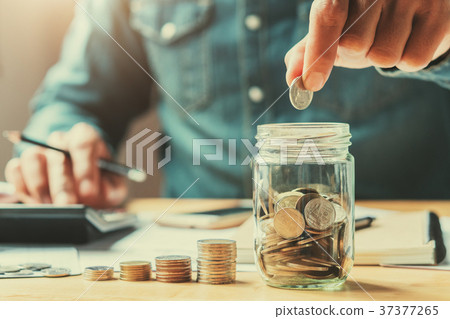 businessman holding coins putting in glass businessman holding coins putting in glass 37377265