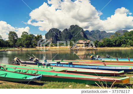 long tail boats on sunset at Song river, Vang Vien long tail boats on sunset at Song river, Vang Vien 37378217