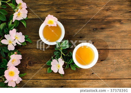 Cup of hot tea with rosehip and blooming flowers Cup of hot tea with rosehip and blooming flowers 37378391