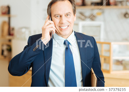 Joyful busy man smiling and holding the cellphone. Joyful busy man smiling and holding the cellphone. 37379235