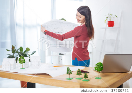 Cheerful engineer smiling while comparing two 37380751