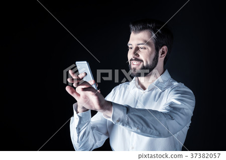 Joyful smart man looking at his smartphone screen Joyful smart man looking at his smartphone screen 37382057