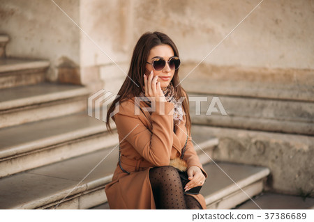 Stylish girl in a brown coat and a scarf with 37386689