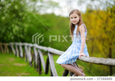 Adorable little girl sitting on a wooden fence Adorable little girl sitting on a wooden fence 37388800