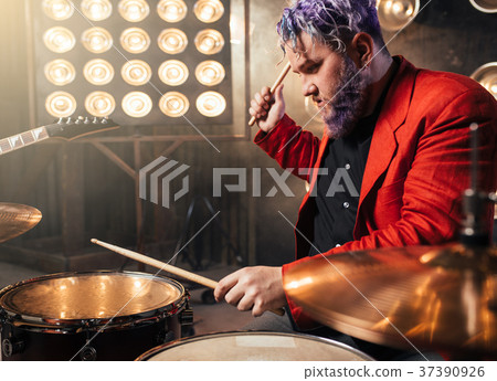 Bearded drummer in red suit, performing on stage 37390926