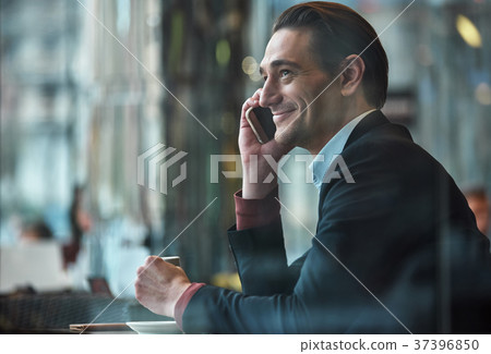 Cheerful man talking by mobile in cafe Cheerful man talking by mobile in cafe 37396850