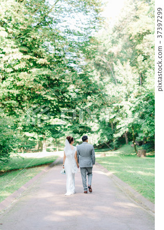Look from behind at groom and bride walking along Look from behind at groom and bride walking along 37397299
