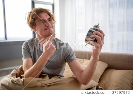 Furious guy getting up with alarm at home 37397973