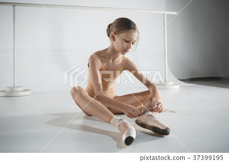 Beautiful little ballerina puting on foot pointe 37399195