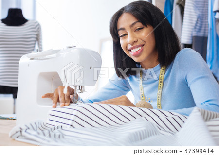 Happy worker of tailor house smiling while sewing 37399414