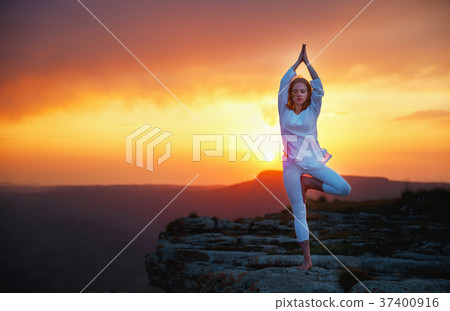 woman practices yoga and meditates   on sunset mountains 37400916