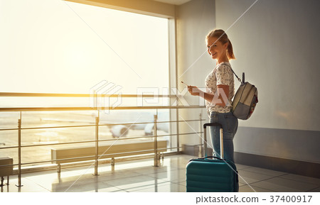 young woman waiting for flying at airport at window with suitcas 37400917
