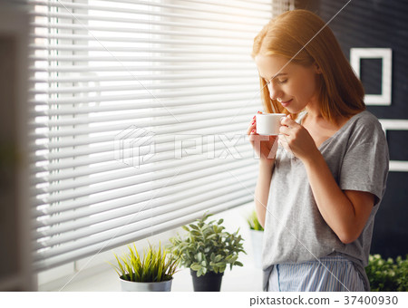 Happy young woman meets morning with cup of coffee at wind Happy young woman meets morning with cup of coffee at wind 37400930