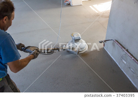 Laborer polishing sand and cement screed floor. 37403395