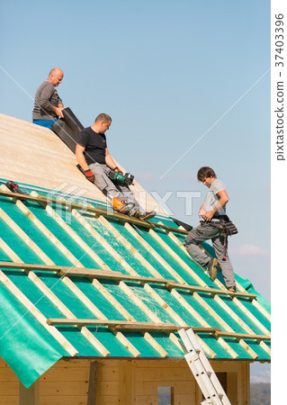 Builders at work with wooden roof construction. 37403396