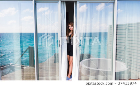 Woman standing in overwater villa room at Maldives.. Woman standing in overwater villa room at Maldives.. 37413974