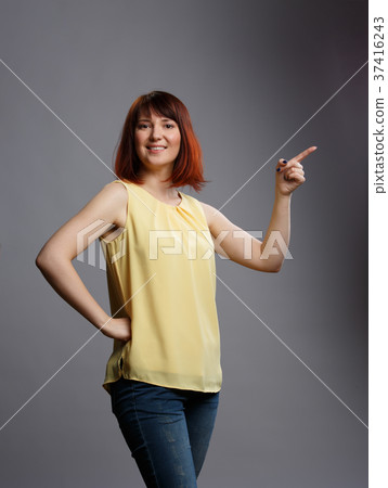 Picture of young brunette pointing finger on gray 37416243