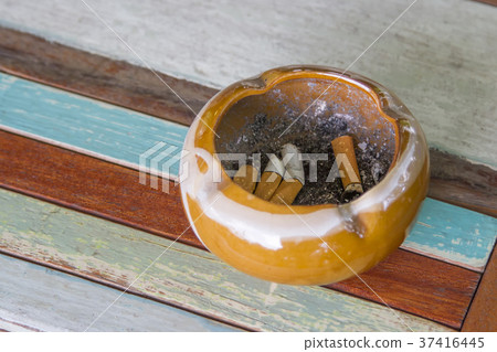 Ashtray and cigarette on a wooden table. 37416445