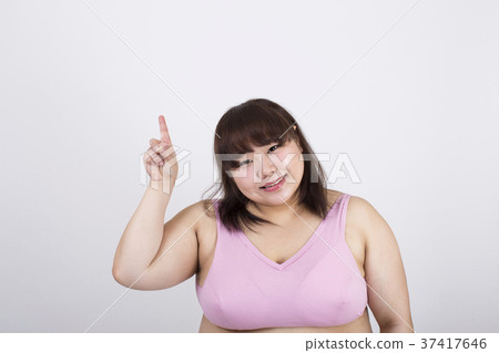 Smiling fat young woman pointing his right index finger up in front of a white background Smiling fat young woman pointing his right index finger up in front of a white background 37417646