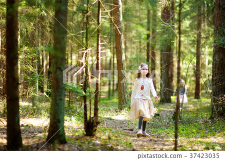 Adorable little girls picking the first flowers of spring in the woods on beautiful sunny spring day 37423035