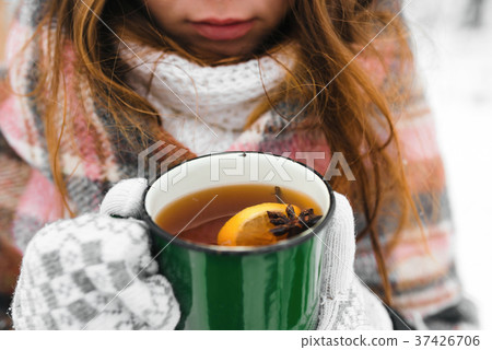 hands in white mittens, holds a green mug of tea,  hands in white mittens, holds a green mug of tea,  37426706