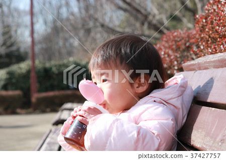 One-year-old child hydration on a park bench 37427757