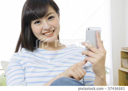 做在長沙發的少婦一個智能手機 37436881