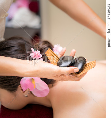 Spa therapist putting hot stone on a woman back Spa therapist putting hot stone on a woman back 37436983