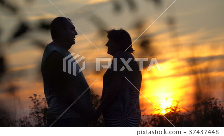 Man and woman facing each other on the sunset background 37437448