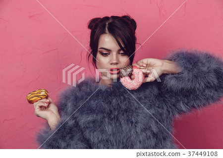 Beautiful girl in a fur coat with donuts in hands Beautiful girl in a fur coat with donuts in hands 37449108
