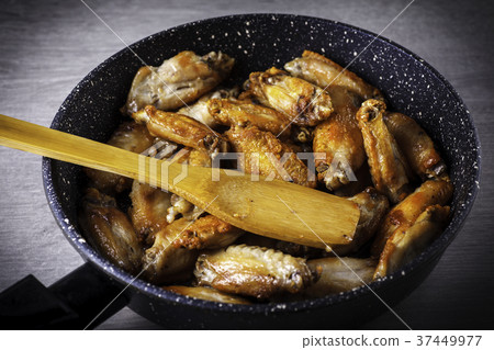 Chicken fried in skillet with wooden spatula Chicken fried in skillet with wooden spatula 37449977