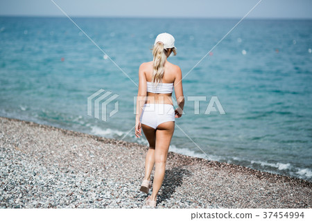 Back view of fitness girl walking along the beach Back view of fitness girl walking along the beach 37454994