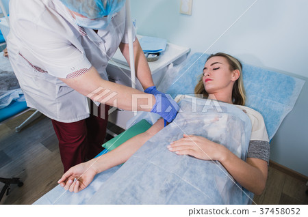 Nurse attaching intravenous tube to patient's hand 37458052