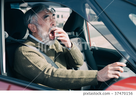Senior male senior driver yawning while driving Senior male senior driver yawning while driving 37470156
