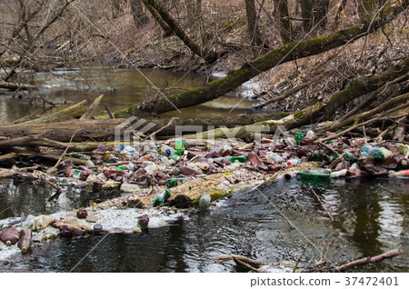View of the polluted small forest river with a lot 37472401